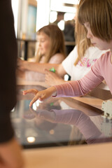 A group of young kids engaged in an interactive learning activity, using a touchscreen table to...