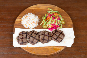 Istanbul kefte, Turkish rice with meat salad mix and local minced meat kebab on a table in a restaurant on a wooden stand