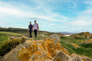 Two people walking through the landscape of the Costa Quebrada in Cantabria