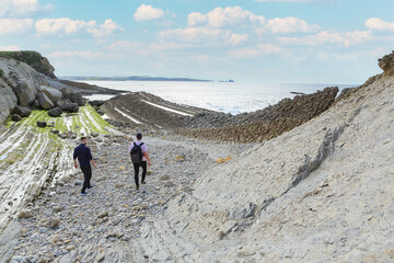 Two people walking through the landscape of the Costa Quebrada in Cantabria