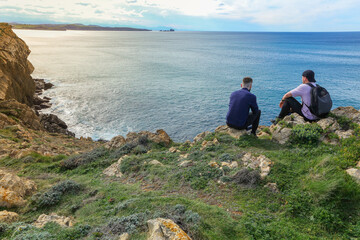 Two people walking through the landscape of the Costa Quebrada in Cantabria
