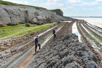 Two people walking through the landscape of the Costa Quebrada in Cantabria
