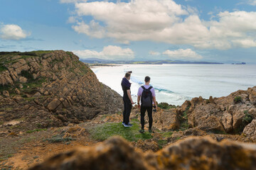 Two people walking through the landscape of the Costa Quebrada in Cantabria