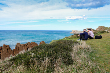 Two people walking through the landscape of the Costa Quebrada in Cantabria