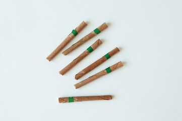 Indian herbal medicinal cigarettes scattered on white background.