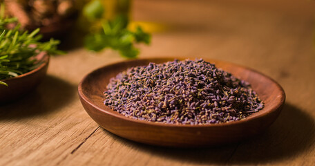 Close-up of dried lavender buds placed on a wooden plate, displayed on a light brown table, for brewing herbal tea or for use in preparing medicine. A precious ingredient in oriental medicine.