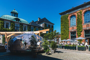 Moderner Pavillon im historischen Innenhof mit begrünter Fassade und Sommeratmosphäre.