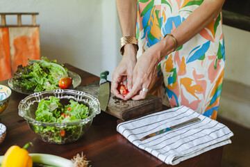 Woman preparing a fresh vegetable salad with lime dressing on a jungle veranda in Sri Lanka. Tropical lifestyle, healthy eating, and colourful ingredients in natural surroundings