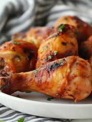 Close up of juicy roasted chicken drumsticks on a white plate with parsley garnish ready to serve studio shot