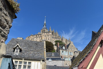 Vue en contre-plongée de l'abbaye du Mont Saint-Michel, derrière les vieux bâtiments à son pied, sous un beau ciel bleu
