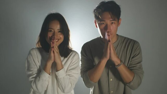 Respectful Greeting: A young man and woman stand side by side, their hands pressed together in a respectful greeting, a gesture of politeness and gratitude.