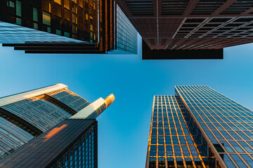 Frankfurter Skyline – Blick nach oben zwischen Hochhäusern bei Sonnenuntergang.