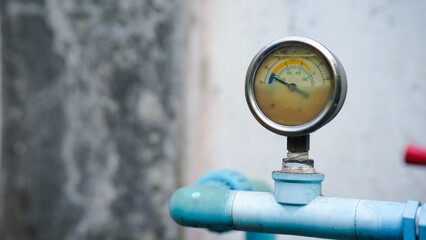 Naklejka premium Pressure gauge on a blue pipe, displaying measurement against a blurred background.