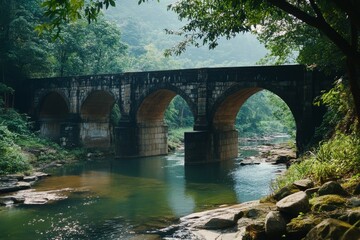 Fototapeta premium Historic stone bridge arches over a tranquil river, nestled amid lush greenery, whispering tales of timeless beauty and serenity.