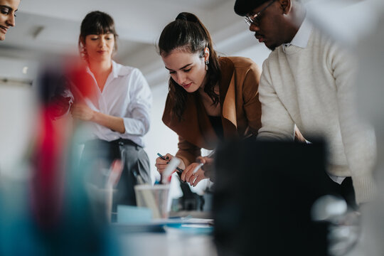A group of professional coworkers collaborate on a project during a business meeting in a modern office environment. The focus on teamwork and strategy highlights their dedication and innovation.