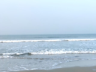 Gentle waves kiss the shore under tranquil skies. The calm ocean stretches endlessly into the horizon, evoking tranquility and peace. 