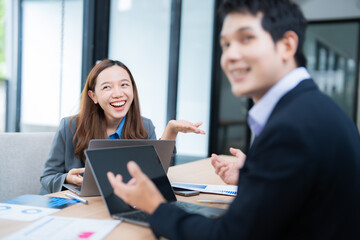 Asian businesspeople engaged in discussion and brainstorming during a corporate meeting, collaborating effectively in a modern office while utilizing a laptop computer for strategy planning