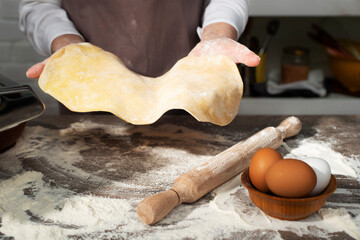 Baking concept. Caucasian female hands showing the stretched dough sheet.