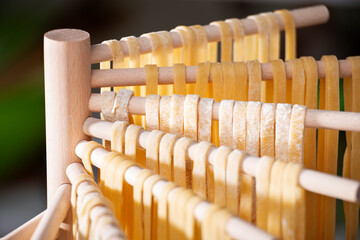 Homemade noodles hanging on wooden dryer rack closeup low angle view
