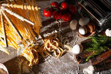 Homemade noodles hanging on wooden dryer rack over messy kitchen table background high angle top view