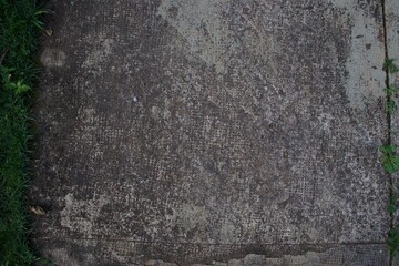 A grey concrete surface with a green grassy border