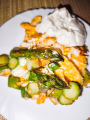 Grilled asparagus, scrambled eggs, and cheese with white sauce on white plate