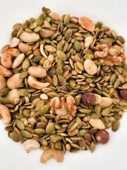 Mix of nuts and pumpkin seeds filling a bowl, healthy snack