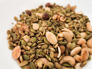 Mix of nuts and seeds filling a white bowl