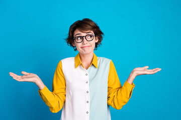 Photo of questioned girl look up empty space shrug shoulders with no answer isolated blue color...