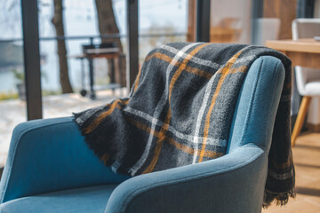 A plaid blanket draped over a blue chair