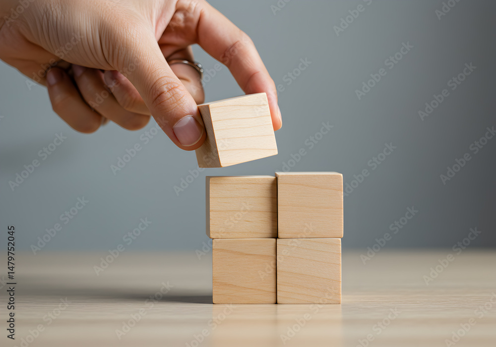 Poster a hand carefully places a wooden block atop a stack of similar blocks illustrating concepts of growt