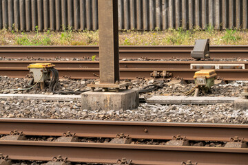 Electrical boxes besides the reailway track with a bunch of orange cables coming out. Behind a...