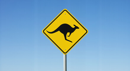 Yellow kangaroo warning road sign against bright blue sky. Traffic caution symbol alerting drivers to wildlife crossing areas used for road safety campaigns and tourism information