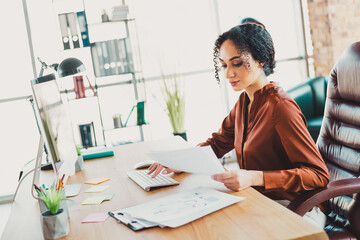 Young professional businesswoman reviewing documents at her desk in a bright and modern office...