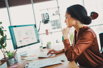 Young businesswoman in a modern office analyzing data on a computer screen while working on professional tasks in a creative workspace