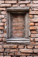 Exposed brick wall featuring an empty rectangular window frame in a rustic structure