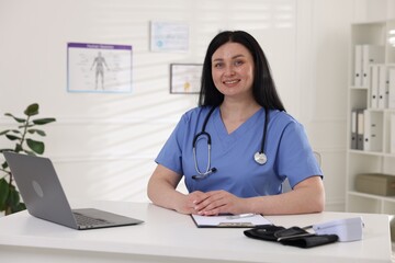 Professional doctor working at white desk in hospital