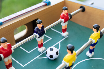Close-up of a foosball table game in action. Miniature players compete for the ball.