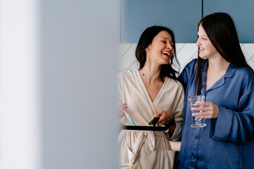 Mature mother and teenager daughter laughing while making breakfast