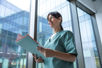 Cute long-haired blonde caucasian woman in lab coat in the clinic corridor