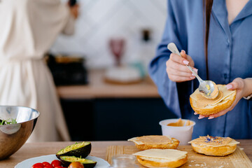 Teenage girl spreading peanut butter on sandwich bun