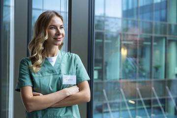 Cute long-haired blonde caucasian woman in lab coat in the clinic corridor