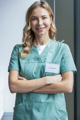 Cute long-haired blonde caucasian woman in lab coat in the clinic corridor