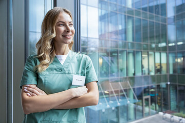 Pretty blonde female doctor in green lab coat near the window in the hospital