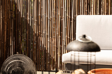Relaxing outdoor scene with bamboo fence and comfy seating. Perfect for summer.