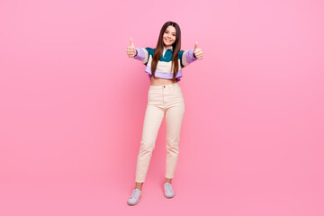 Photo Of Young cheerful cute teenager girl in casual stylish outfit giving thumbs up on pink background