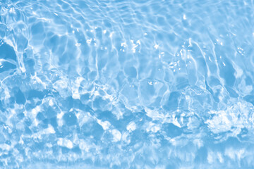 Blue water with ripples on the surface. Defocus blurred transparent blue colored clear calm water surface texture with splashes and bubbles. Water waves with shining pattern texture background.