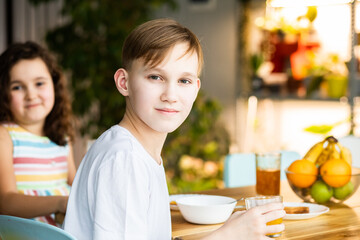 Happy family sister and brother have breakfast with cereal and milk in a kitchen at home