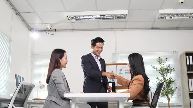 Business colleagues discussing a project and shaking hands in agreement, showcasing teamwork and successful collaboration in a modern office environment