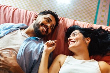 Couple sharing a cheerful moment together lying on a colorful bedspread